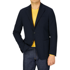 Man wearing a Canali navy cotton jersey unconstructed blazer over a yellow shirt paired with blue jeans.