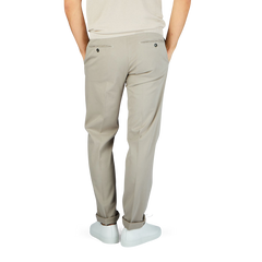 The man is wearing Stone Beige Cotton Stretch Flat Front Chinos by Canali, showcasing a stylish and sophisticated look.