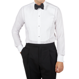 A man wearing a formal Canali White Cotton Double Cuff Pleated Dress Shirt and black pants.