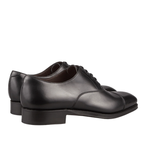 A pair of Carmina Black Calf Leather Captoe Rain Oxford Shoes against a dark background.
