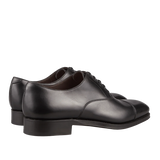 A pair of Carmina Black Calf Leather Captoe Rain Oxford Shoes against a dark background.