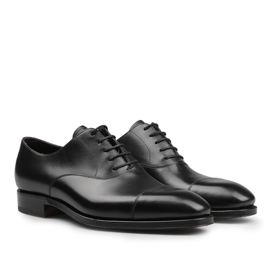 These Black Calf Leather Captoe Rain Oxford Shoes from Carmina are crafted in fine black leather and feature a classic lace-up design. Their sleek appearance with rounded toes highlights their versatile style, while the Goodyear welted construction ensures lasting durability and timeless elegance.