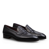 A pair of Carmina Black Calf Leather Uetam Penny Loafers with durable construction against a dark background.