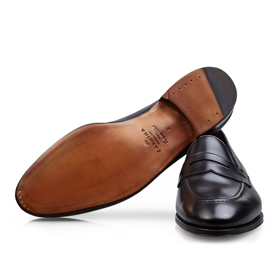 A single Carmina black calf leather Uetam penny loafer lying on its side with the sole facing up.