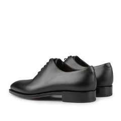 A pair of Black Calf Leather Wholecut Rain Oxford Shoes from Carmina is elegantly displayed at an angle, highlighting their polished finish and simple design. Featuring Goodyear welted construction, these timeless classics promise durability and style.