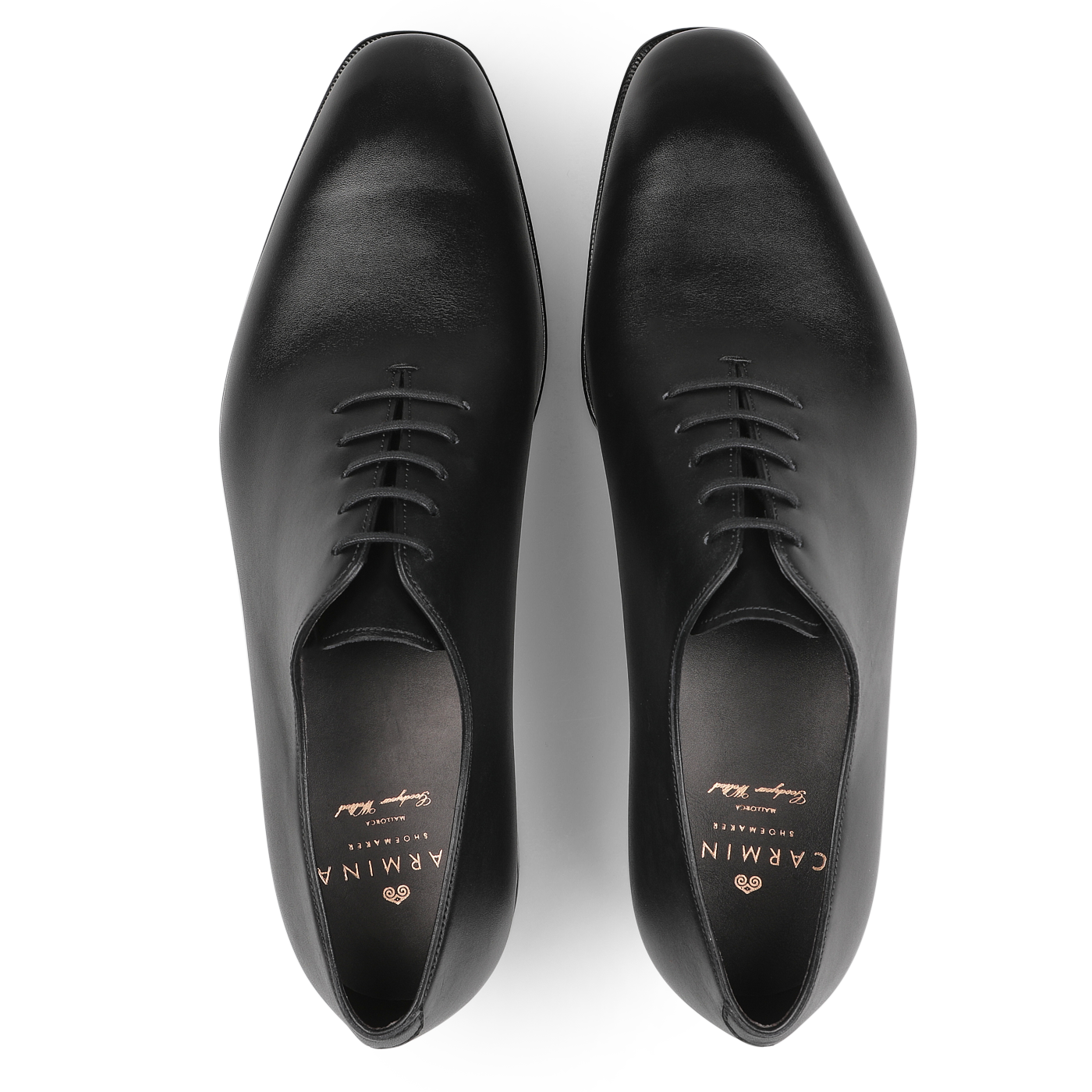 A pair of Carmina's Black Calf Leather Wholecut Rain Oxford Shoes, viewed from above, featuring a polished finish and laces that showcase the elegance of Goodyear welted construction.