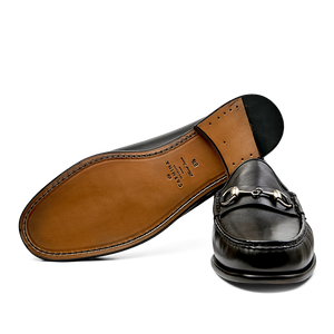 A single black Funchal Leather Xim Horsebit loafer by Carmina displayed above its sole.