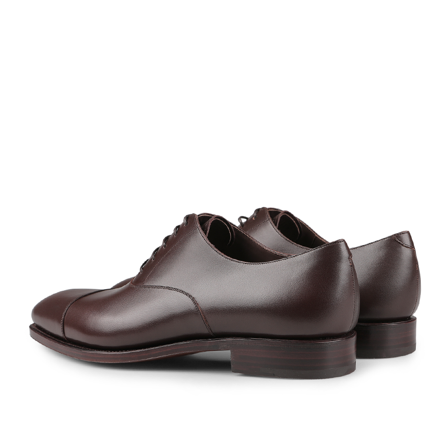 The Carmina Brown Calf Rain Captoe Rain Oxford Shoes feature a classic design with laced fronts and are crafted on a Goodyear welt, shown from a rear angle.