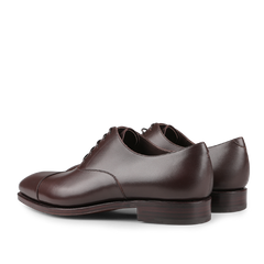 The Carmina Brown Calf Rain Captoe Rain Oxford Shoes feature a classic design with laced fronts and are crafted on a Goodyear welt, shown from a rear angle.