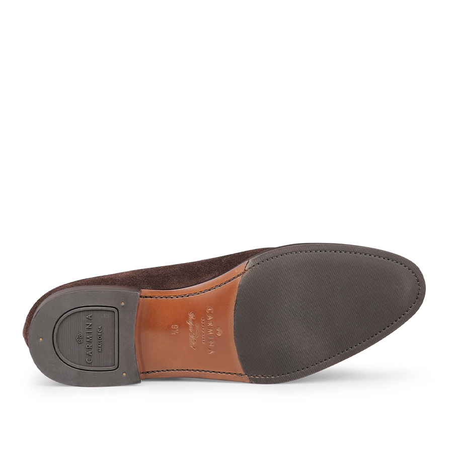 The Brown Suede Forest Rubber Penny Loafers by Carmina feature a durable rubber grip sole with visible stitching, showcasing branding details on the heel.