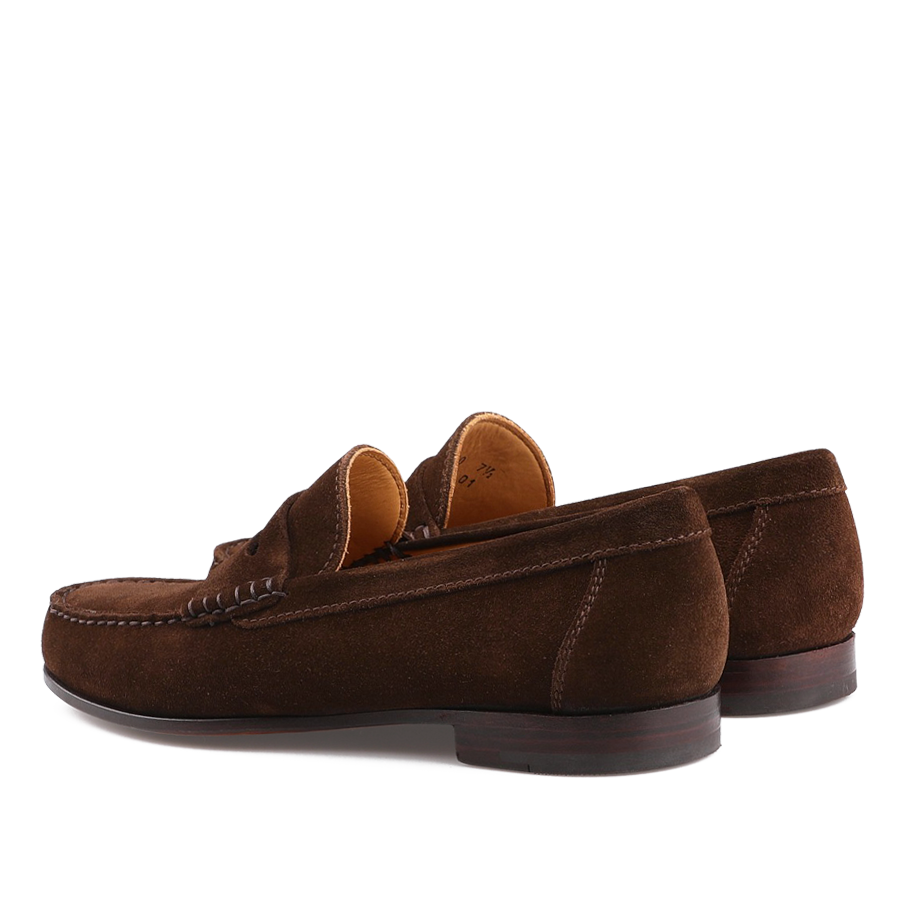 Chocolate Repello Suede Xim Penny Loafers by Carmina feature visible stitching, a low heel, and a tan inner lining. Crafted using durable Blake rapid construction, they are positioned with one slightly ahead of the other.