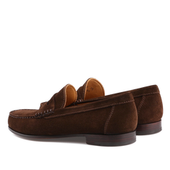 Chocolate Repello Suede Xim Penny Loafers by Carmina feature visible stitching, a low heel, and a tan inner lining. Crafted using durable Blake rapid construction, they are positioned with one slightly ahead of the other.