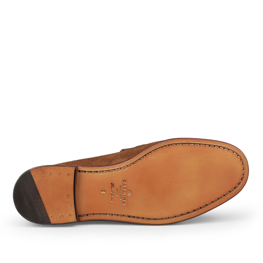 A brown leather shoe sole with stitching, adorned with metal details and a textured heel for enhanced grip. The Carmina Tobacco Suede Leather Xim Horsebit Loafers elegantly feature tobacco suede leather accents that perfectly complement their sophisticated design.