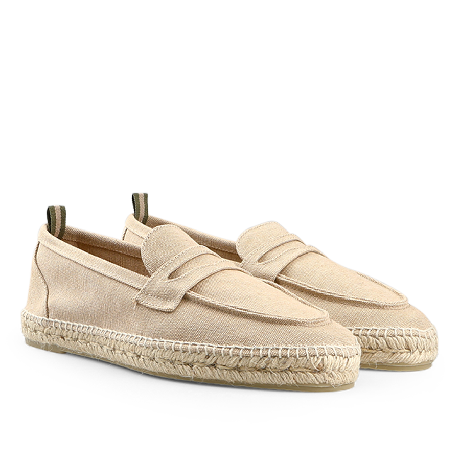 The Sand Beige Cotton Canvas Nacho Espadrilles by Castañer are slip-on shoes crafted with cotton canvas, featuring woven jute soles and a decorative strap across the top.