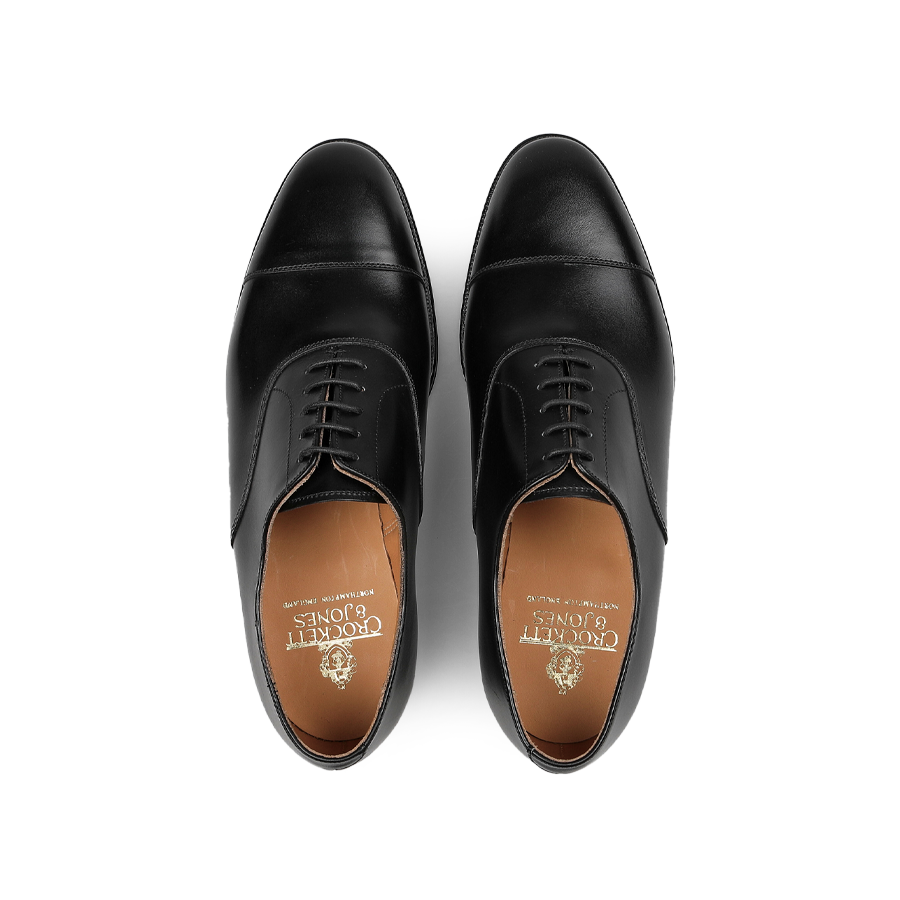 Crafted by Crockett & Jones, the Black Calf Leather Connaught Cap Oxfords showcase a polished silhouette and lace-up design. Made from premium black calf leather, their Goodyear-welted construction ensures durability and timeless elegance when viewed from above.