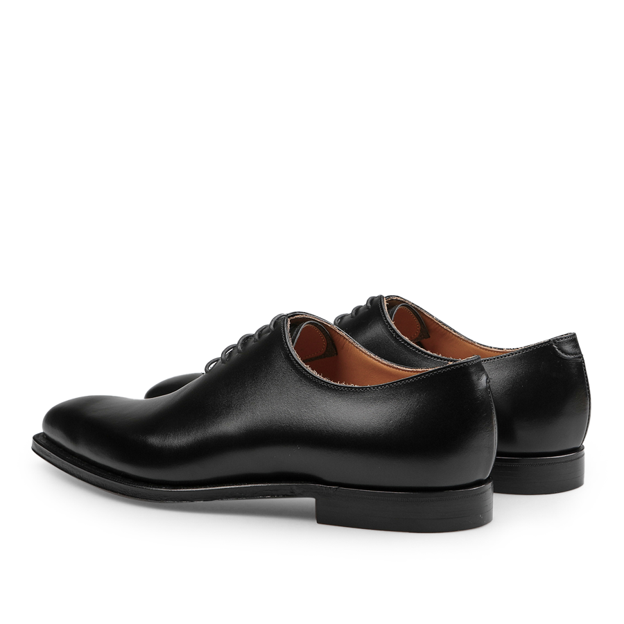 The Black Calf Leather Alex Wholecuts by Crockett & Jones feature a polished finish and laced design, highlighting their exceptional Goodyear-welted craftsmanship when viewed from the side and slightly behind.