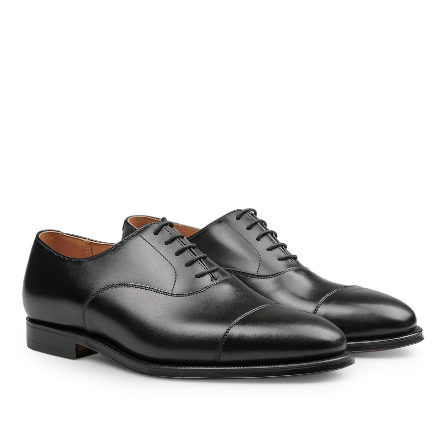 The Black Calf Leather Connaught Cap Oxfords by Crockett & Jones are crafted in fine calf leather, showcasing a Goodyear-welted construction with a lace-up closure and a sleek finish.