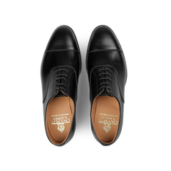 Top view of a pair of Black Calf Leather Connaught II Cap Oxfords by Crockett & Jones, featuring fine calf leather with tan insoles and a city rubber sole.