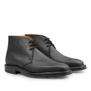 A pair of Black Rough-Out Suede Molton Boots by Crockett & Jones, featuring Goodyear welted craftsmanship with black laces and brown soles, showcased against a pristine white background.