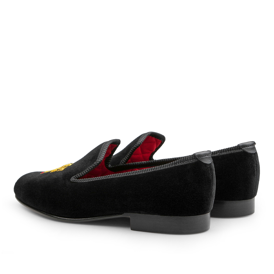 Crockett & Jones Black Velvet Lion Rampant Albert Slippers featuring a luxurious red interior and intricate hand-embroidered detail on top, displayed from a rear side angle.