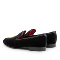 Crockett & Jones Black Velvet Lion Rampant Albert Slippers featuring a luxurious red interior and intricate hand-embroidered detail on top, displayed from a rear side angle.