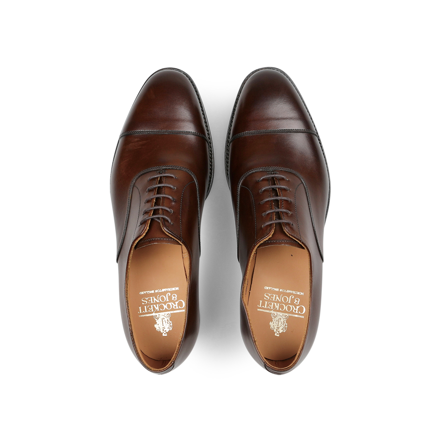 Top view of a pair of Crockett & Jones Dark Brown Burnished Calf Connaught Cap Oxfords, showcasing straight cap oxfords with laces on a white background.