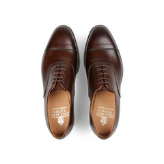 Top view of a pair of Crockett & Jones Dark Brown Burnished Calf Connaught Cap Oxfords, showcasing straight cap oxfords with laces on a white background.