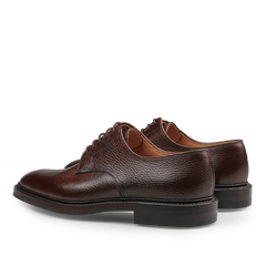 The Dark Brown Country Calf Grain Ashdown Derbies from Crockett & Jones, made with Goodyear-welted construction and laces, showcase a textured finish. Displayed on a white backdrop, these shoes exude an elegant and timeless style when viewed from the back and side.