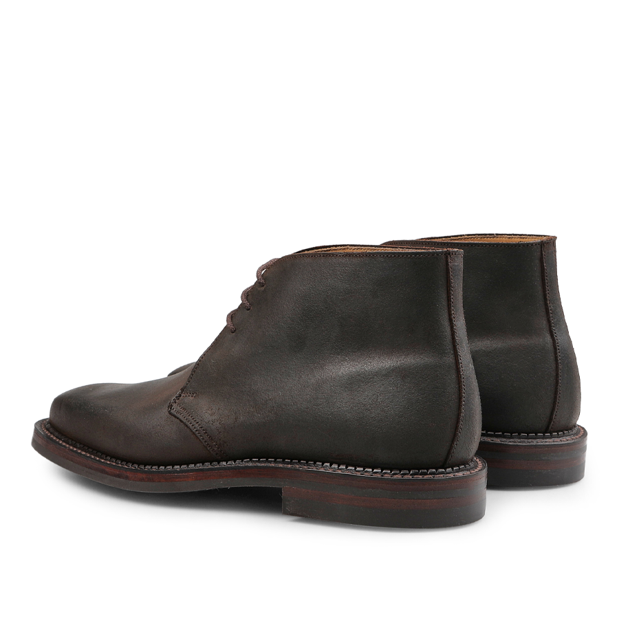 A pair of Dark Brown Rough-Out Suede Molton Boots by Crockett & Jones, viewed from the back at an angle, highlights the timeless elegance of Goodyear welted craftsmanship.