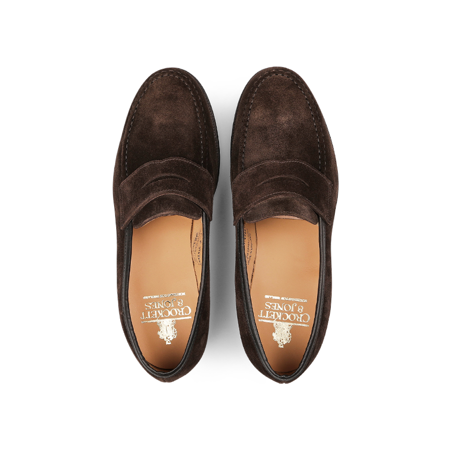 A pair of Dark Brown Suede Leather Boston Loafers from Crockett & Jones, viewed from above, highlight decorative stitching and the brand's logo on the leather insole. Expertly crafted and Goodyear-welted for durability, these loafers encapsulate timeless elegance.