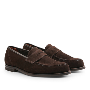 Positioned side by side on a plain background is a pair of Crockett & Jones Dark Brown Suede Leather Harvard II Loafers, showcasing their stitching details and low heels.