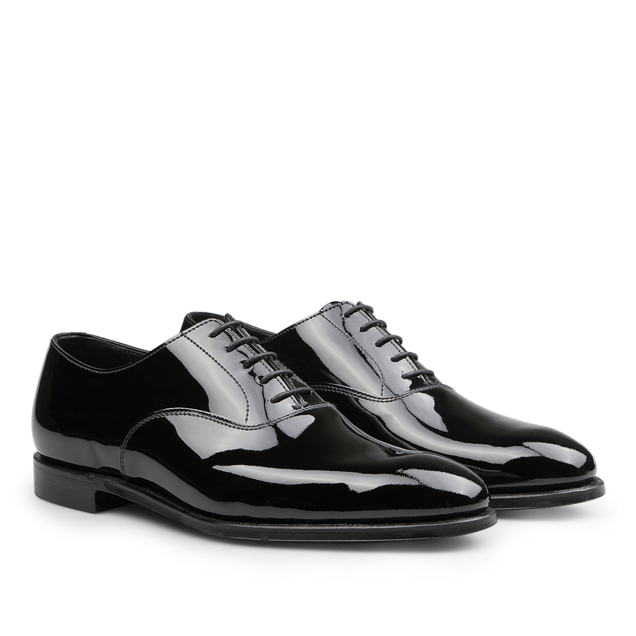 The Black Patent Calf Leather Overton Oxfords by Crockett & Jones are beautifully crafted, featuring a sleek black patent calf leather design that elegantly shines against a white background, finished with meticulously tied black laces.