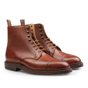 A pair of Tan Scotch Grain Leather Coniston Boots by Crockett & Jones, showcasing a textured finish, cap toe design, metal eyelets, and pull tabs at the back, reminiscent of the classic derby boot style.