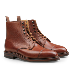 A pair of Tan Scotch Grain Leather Coniston Boots by Crockett & Jones, showcasing a textured finish, cap toe design, metal eyelets, and pull tabs at the back, reminiscent of the classic derby boot style.