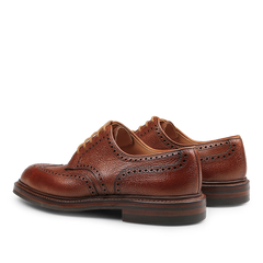 Tan Pembroke brogues by Crockett & Jones, made from luxurious Scotch grain leather, highlight intricate perforations and durable Goodyear-welted soles, shown from a rear and angled perspective.