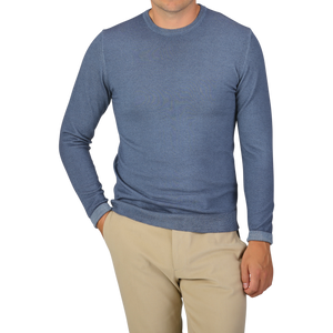 A person wearing a Daniele Fiesoli Dark Blue Melange Merino Wool Crewneck and beige pants stands with one hand in their pocket against a plain background.