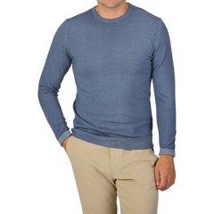 A person wearing a Daniele Fiesoli Dark Blue Melange Merino Wool Crewneck and beige pants stands with one hand in their pocket against a plain background.