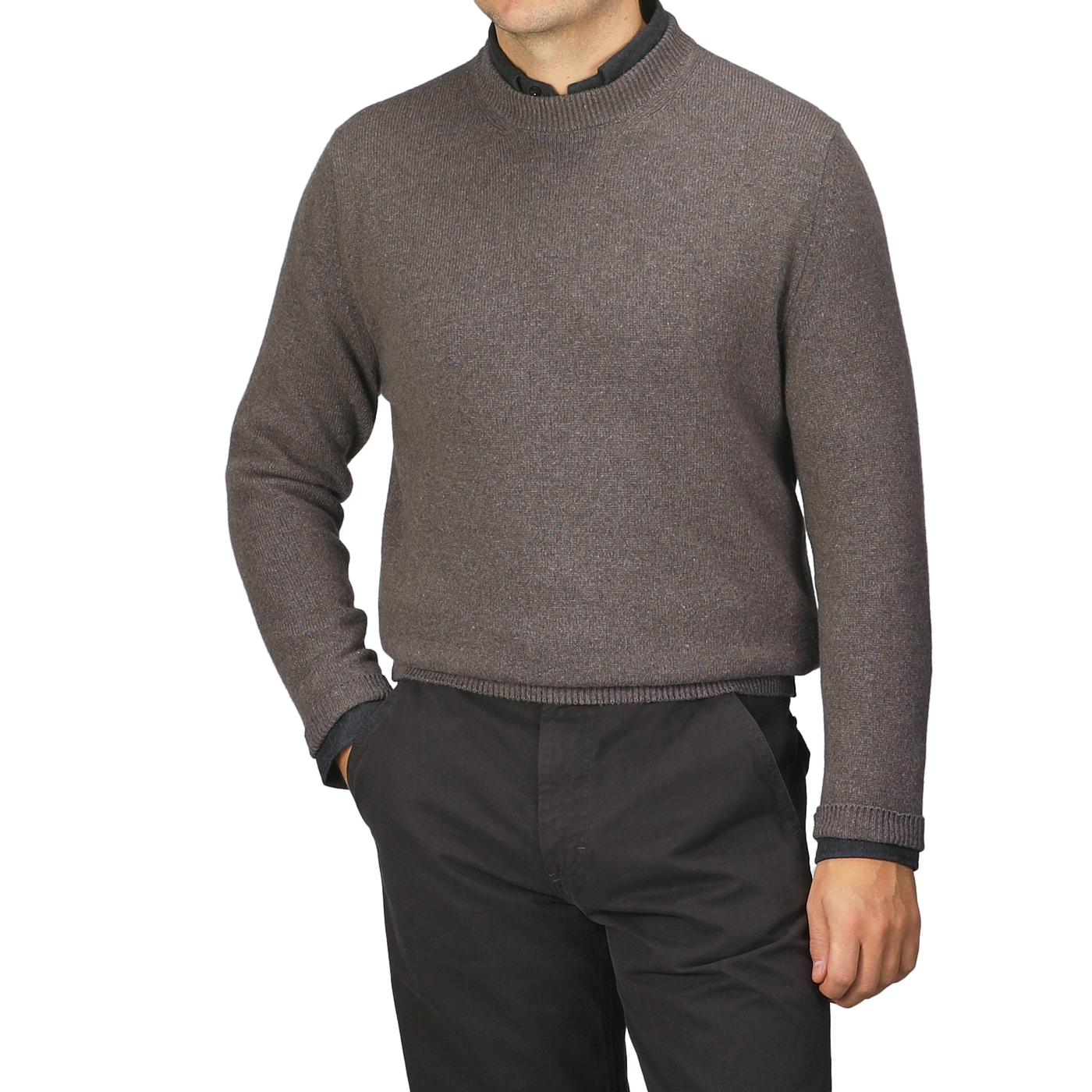 A man wearing a Corteccia Brown Cashmere Crewneck Sweater by Daniele Fiesoli and dark pants stands with one hand in his pocket.