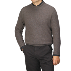 A man wearing a Corteccia Brown Cashmere Crewneck Sweater by Daniele Fiesoli and dark pants stands with one hand in his pocket.