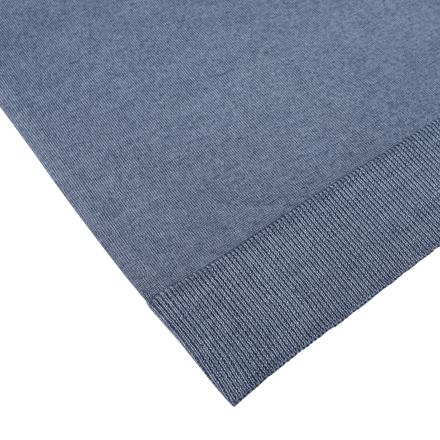 Close-up of the edge of a dark blue melange knit fabric garment laid flat on a white surface. Made in Italy by Daniele Fiesoli, this extra fine merino wool fabric appears soft and finely woven, with a ribbed hem.