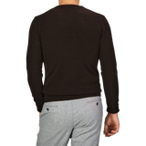 A person wearing a Daniele Fiesoli Dark Brown Wool Cashmere Crewneck and light gray pants is standing with their back turned to the camera.