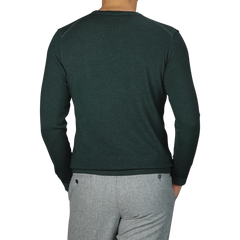 A person wearing a dark green Merino wool crewneck sweater by Daniele Fiesoli, made in Italy, paired with light gray pants, shown from the back.