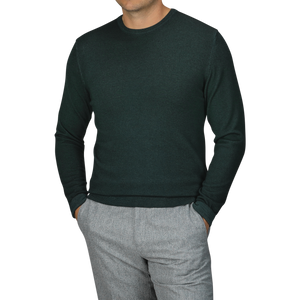 A person wearing the Dark Green Wool Cashmere Crewneck by Daniele Fiesoli, crafted in Italy from a luxurious wool-cashmere blend, paired with gray trousers and hands in pockets.