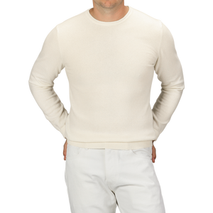 A person wearing a Daniele Fiesoli Ecru Wool Cashmere Crewneck and white pants, standing with hands in pockets, showing their torso and upper legs.