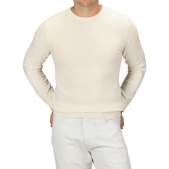 A person wearing a Daniele Fiesoli Ecru Wool Cashmere Crewneck and white pants, standing with hands in pockets, showing their torso and upper legs.