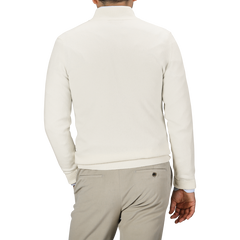 A person wearing an Ecru Wool Cashmere Quarter Zip Sweater by Daniele Fiesoli and beige pants is seen from behind.