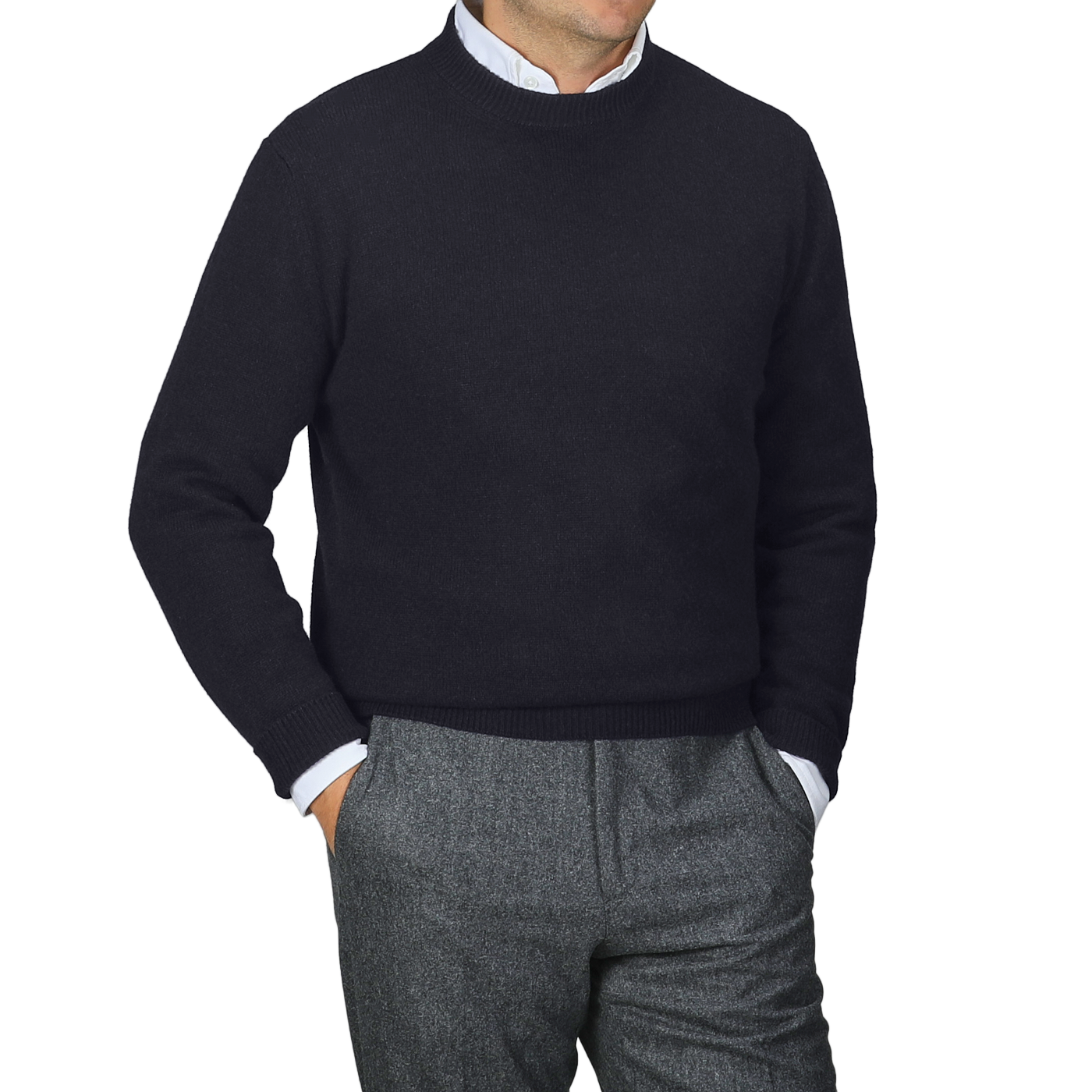 A person stands against a gray backdrop, stylishly wearing the Navy Blue Cashmere Crewneck Sweater by Daniele Fiesoli over a white collared shirt, paired with gray pants.