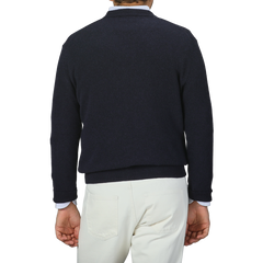 A person is seen from behind against a gray background, wearing a Daniele Fiesoli Navy Blue Cashmere V-Neck Sweater made in Italy paired with white pants.