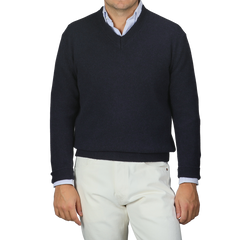 A person is stylishly dressed in a Daniele Fiesoli Navy Blue Cashmere V-Neck Sweater, crafted from upcycled cashmere, over a light blue collared shirt paired with crisp white pants.