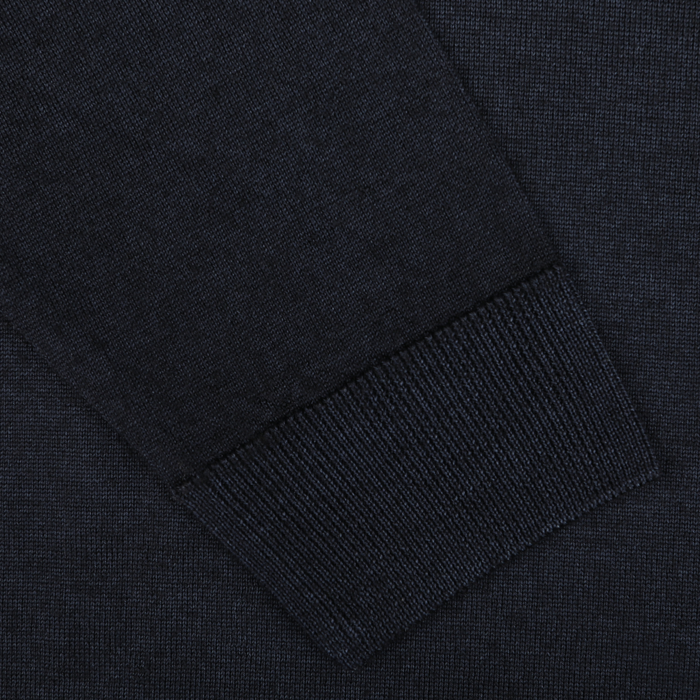 Close-up of a dark fabric sleeve with a ribbed cuff. The texture of the Navy Blue Melange Merino Wool Crewneck by Daniele Fiesoli and the stitching details are clearly visible—expertly crafted by knitwear specialists for a regular fit.